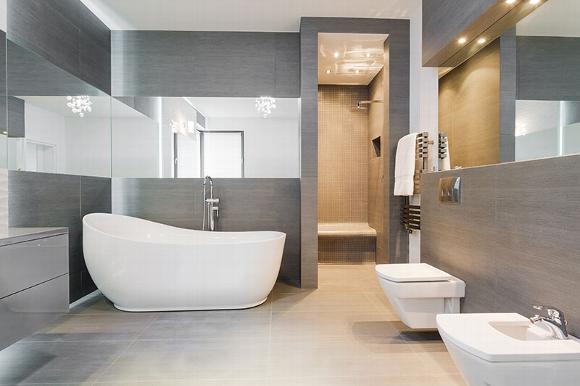 Grey minimalist bathroom with slipper bath and large mirrors